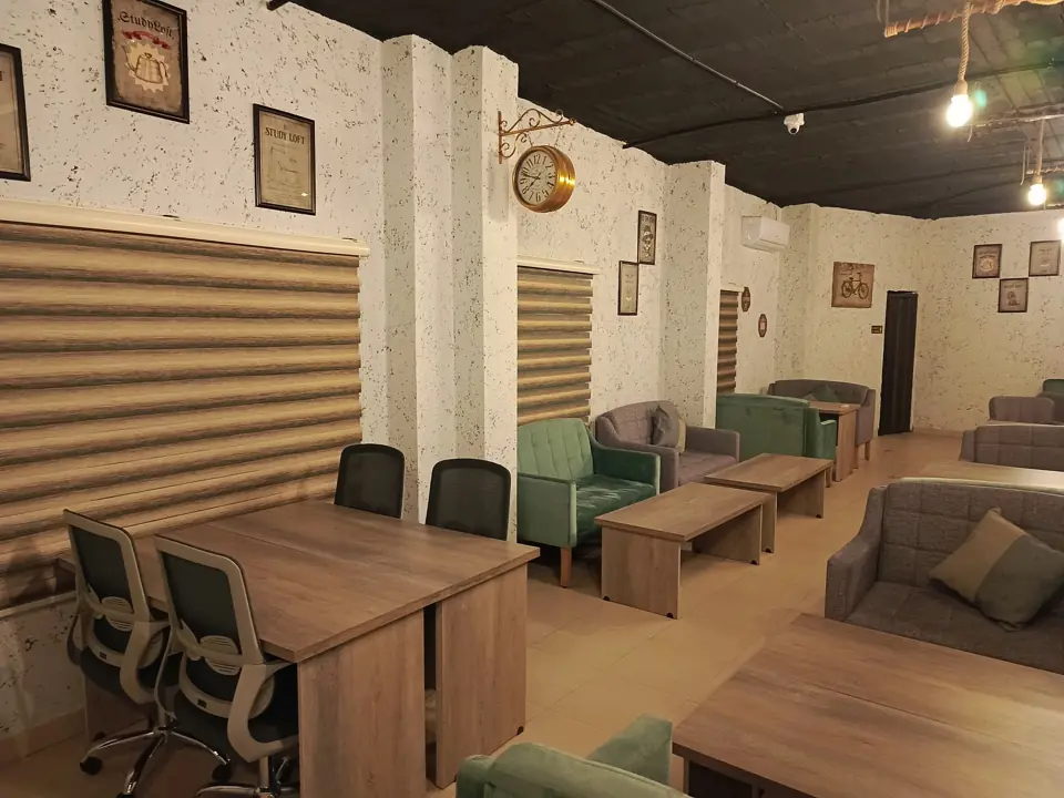 مكاتب فردية للدراسة ومقاعد مريحة أسفل لوحات كلاسيكية في ستدي لوفت
